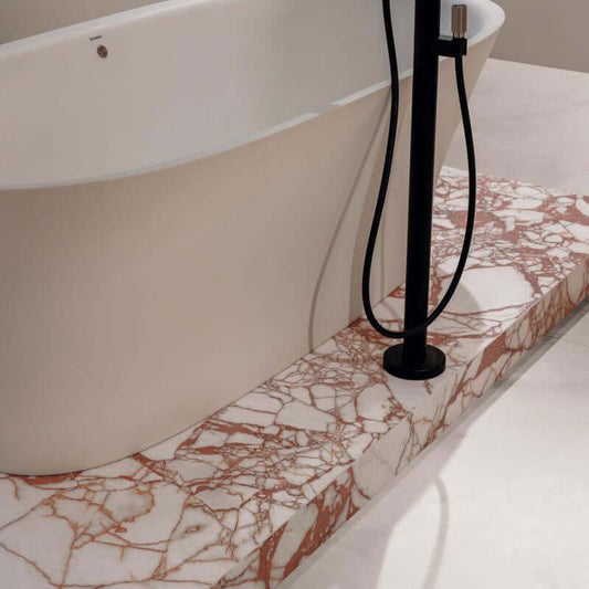 Tegel detail with elegant marble design near a modern bathtub and sleek black shower fixture.