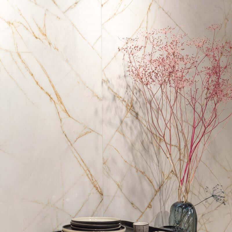 Tegel met marmerlook in goud- en witte tinten, decoratief met een vaas en gedroogde bloemen.