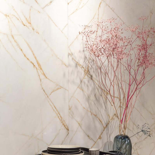 Tegel met marmerlook in goud- en witte tinten, decoratief met een vaas en gedroogde bloemen.