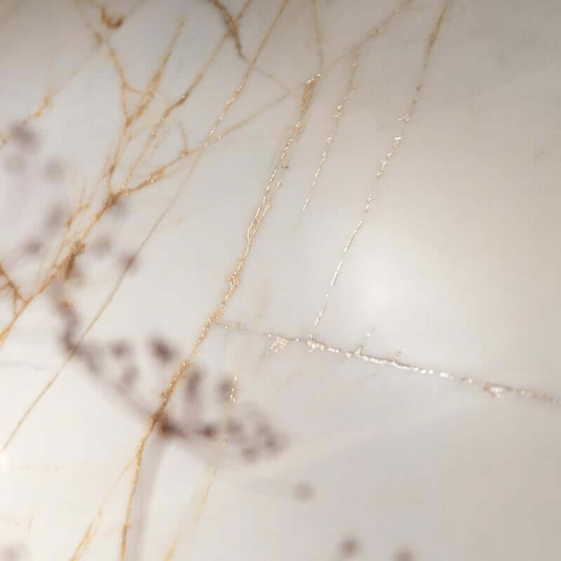 Tegel with a glossy marble finish featuring delicate gold and beige veining.